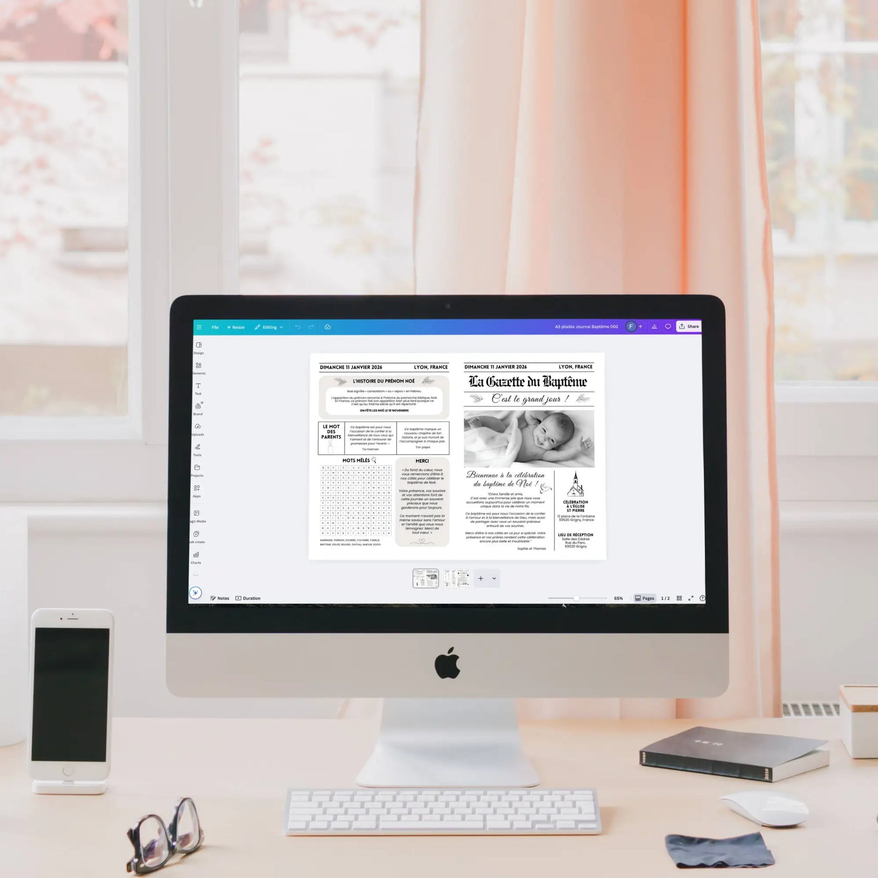 Écran d’ordinateur affichant dans Canva une gazette de baptême élégante en noir et blanc en cours de personnalisation, posée sur un bureau lumineux avec clavier, smartphone et lunettes.