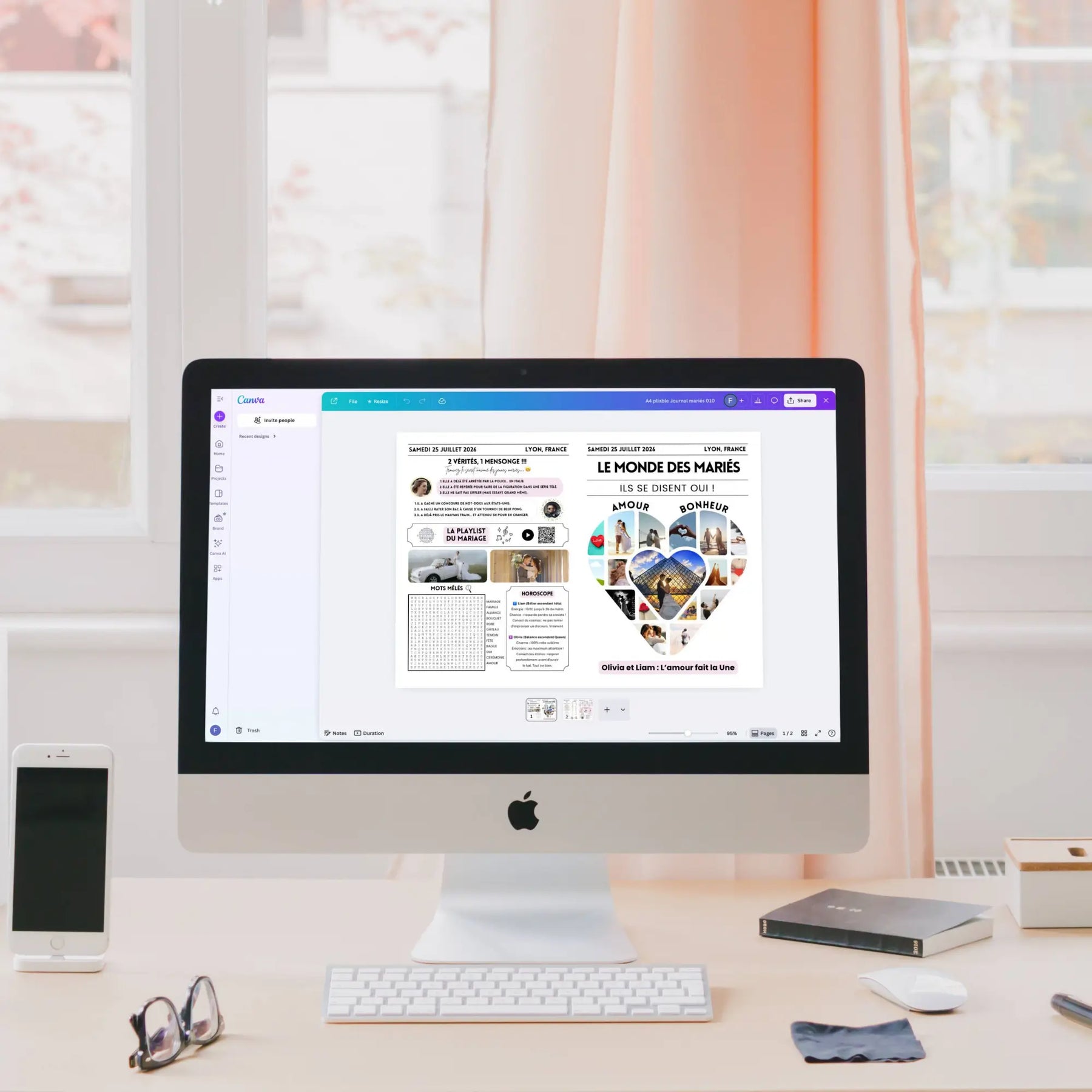 Écran d’ordinateur iMac affichant dans Canva la maquette d’une gazette des mariés love. ureau avec clavier, souris, lunettes, iPhone, disque dur et fenêtre en arrière-plan avec rideaux roses.