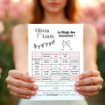 Charger l'image dans la visionneuse de la galerie, Invitée tenant à deux mains une feuille de bingo de mariage personnalisée «Le Bingo des Amoureux », avec cases à cocher humoristiques et instructions de jeu, sur fond de fleurs floues.
