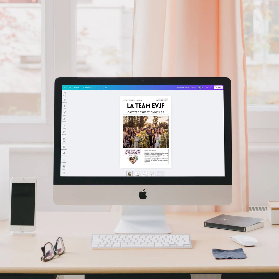 Sur l’écran d’un iMac, la Gazette EVJF originale est ouverte dans l’éditeur Canva, affichant une couverture avec une photo de groupe de femmes dans un vignoble et la mention 'Elle a dit OUI le 03/03/2025'.