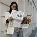 Charger l'image dans la visionneuse de la galerie, Une femme élégante en blazer blanc lit la Gazette EVJF originale.
