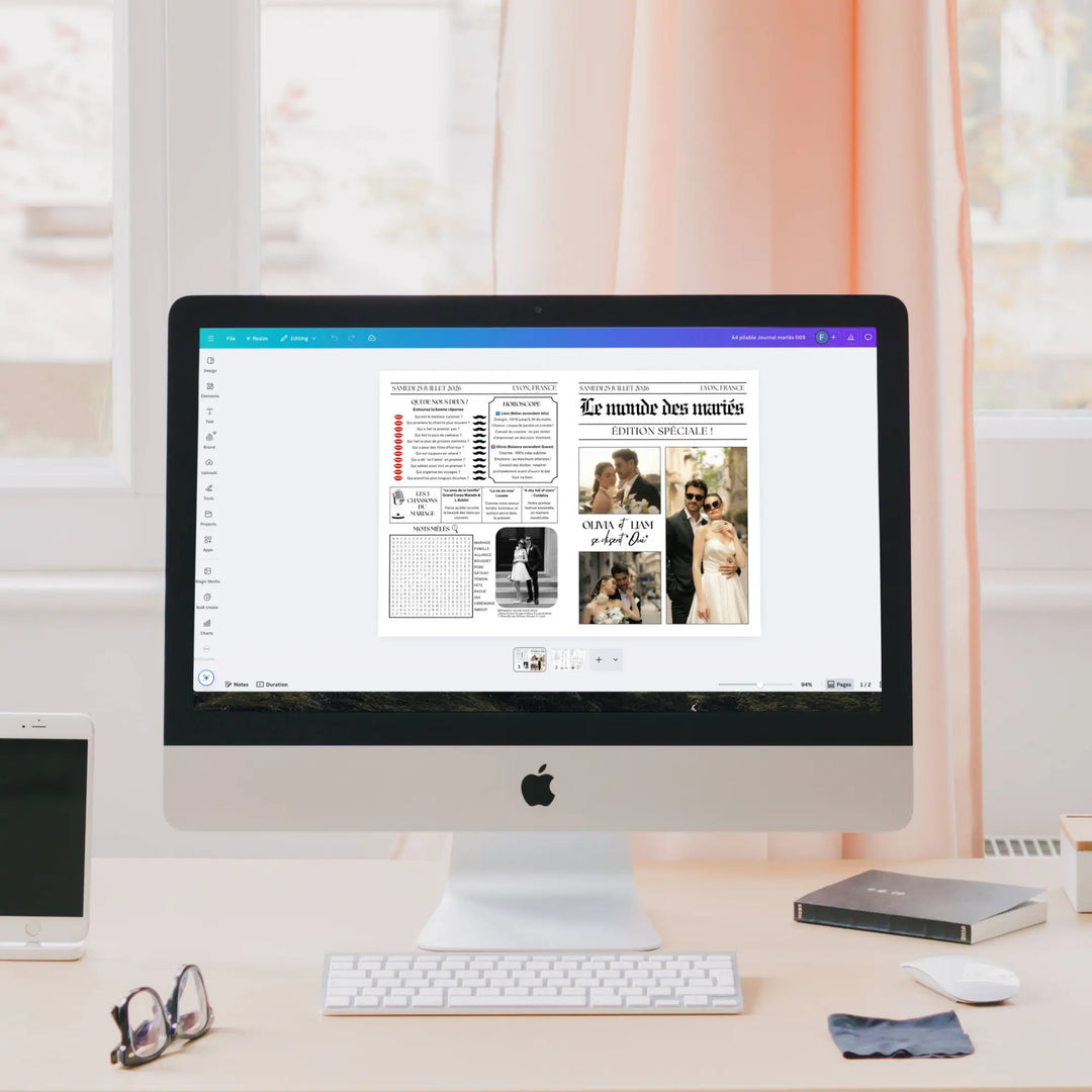 Écran d’ordinateur iMac affichant dans Canva la mise en page d’une gazette de mariage originale. Sur le bureau, un iPhone, des lunettes et un disque dur externe.