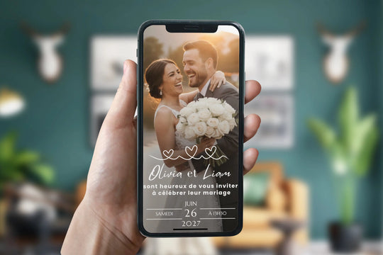 Main tenant un téléphone sur lequel s'affiche un site de mariage pour un faire-part mariage personnalisé.
