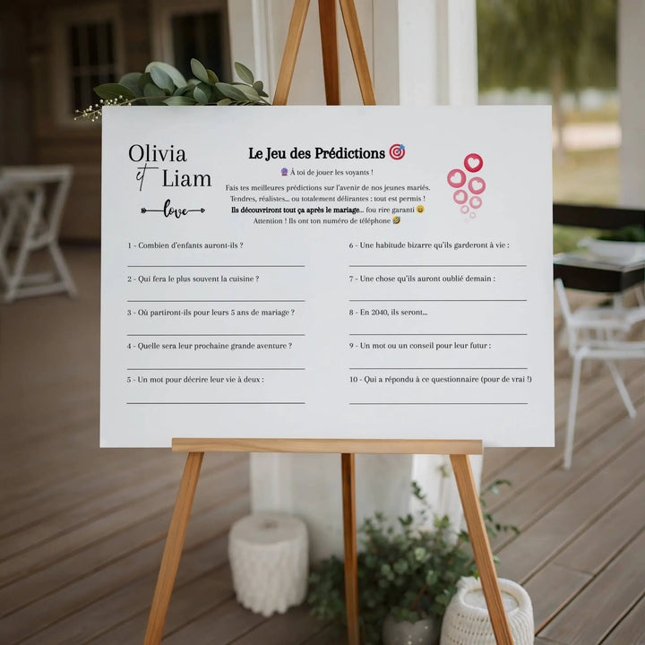 Affiche de jeu de mariage “Le jeu des prédictions” posée sur un chevalet bois lors d’une réception, prête à être remplie par les invités.