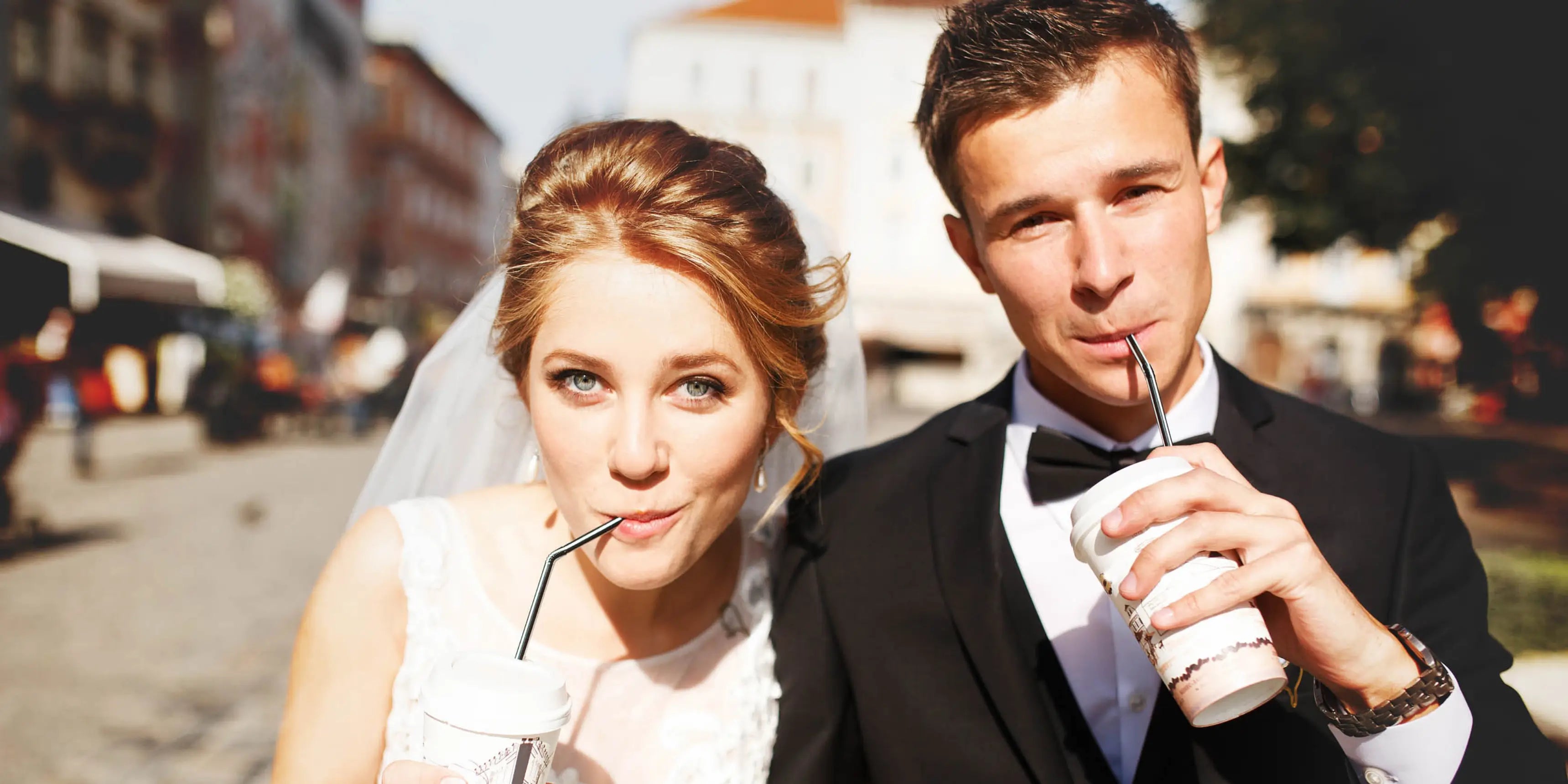 Photo de deux jeunes mariés décontractés et modernes, ils boivent une boisson avec une paille.