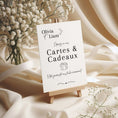 Charger l'image dans la visionneuse de la galerie, Panneau de mariage personnalisé “Cartes & Cadeaux” au nom d’Olivia & Liam, imprimé sur papier texturé et présenté sur un petit chevalet en bois, entouré de fleurs de gypsophile et de tissu ivoire élégant.
