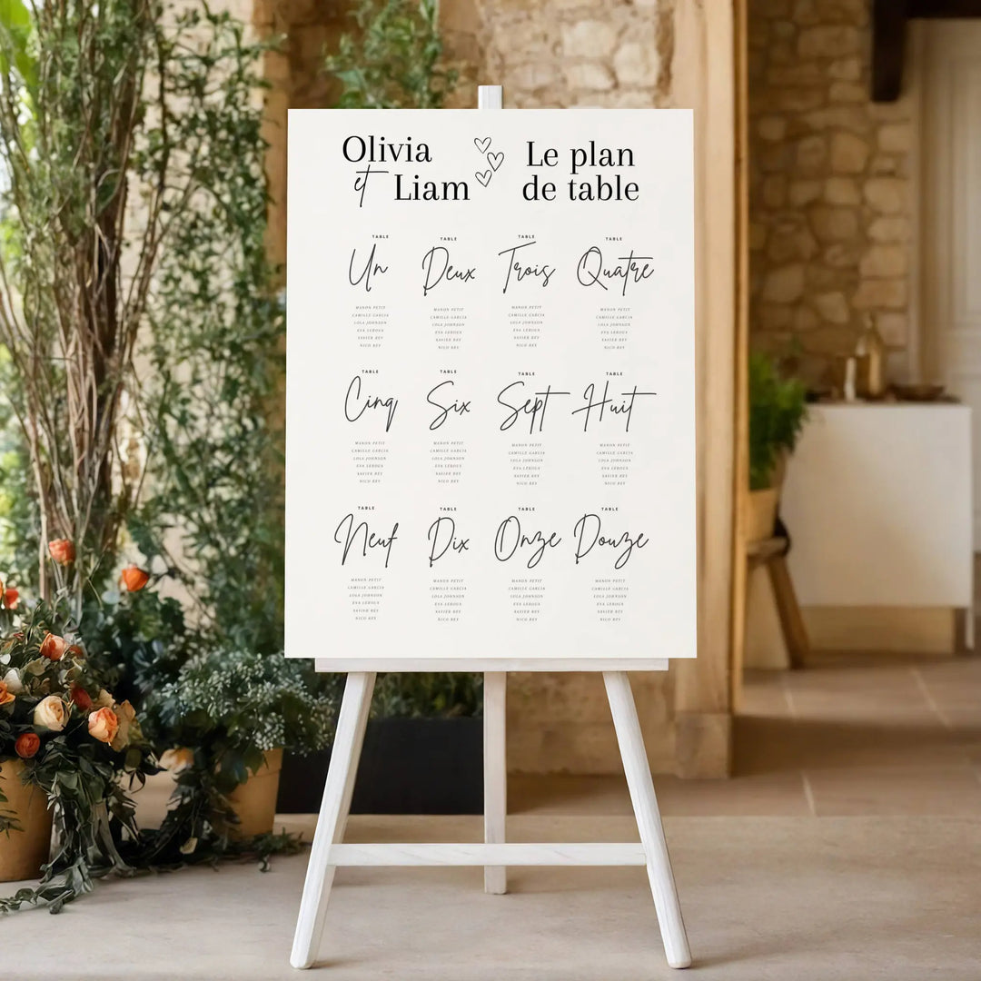 Plan de table mariage élégant sur chevalet, affiche personnalisée avec prénoms des mariés et numéros de table, décoration de réception chic avec fleurs.